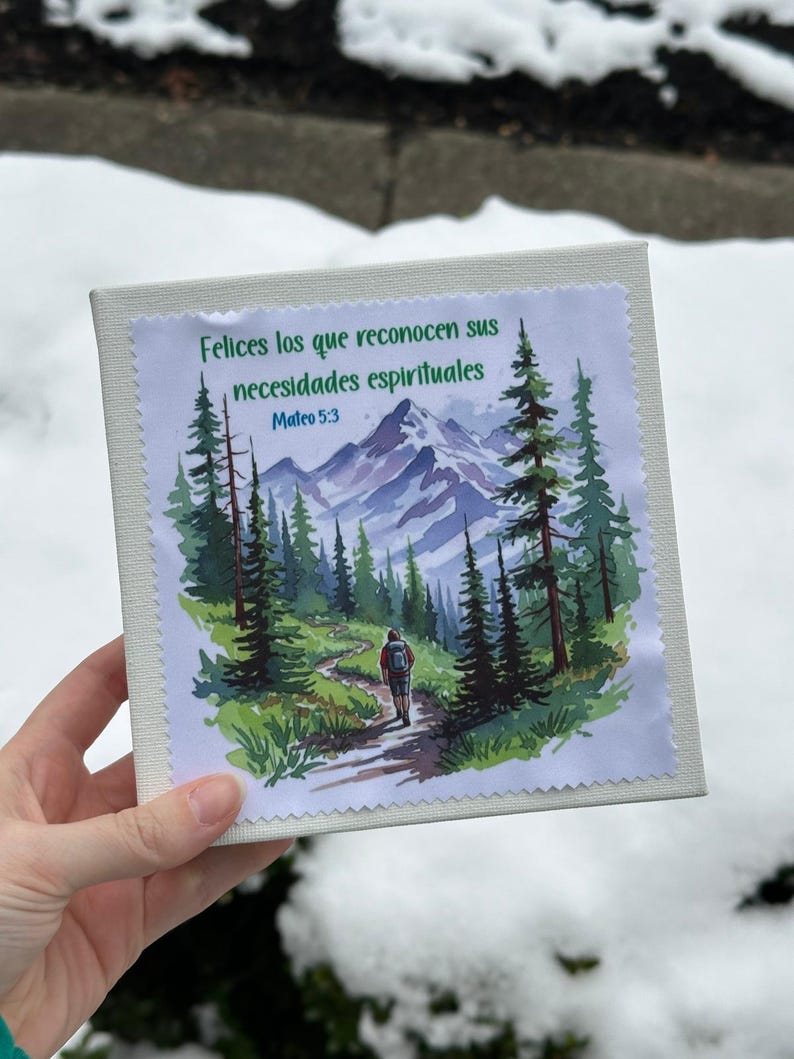 Puede incluir: Un lienzo cuadrado blanco roto con una imagen impresa de una escena de monta&ntilde;a y texto en espa&ntilde;ol. La imagen muestra a una persona caminando por un sendero a trav&eacute;s de un bosque, con monta&ntilde;as al fondo. El texto dice "Felices los que reconocen sus necesidades espirituales Mateo 5:3."