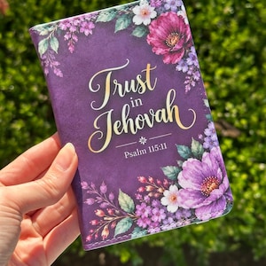 May include: A rectangular purple cover featuring a floral design with pink, purple, and white flowers and green leaves. The text "Trust in Jehovah" is printed in gold script, with "Psalm 115:11" written below it in a smaller white font.