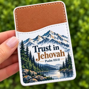 Puede incluir: Un tarjetero adhesivo rectangular para teléfono con un bolsillo superior marrón y una sección inferior blanca con un paisaje de montaña, bosque y lago. El texto dice Trust in Jehovah Psalm 115:11 en azul oscuro y marrón.