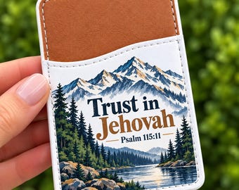 Puede incluir: Un tarjetero adhesivo rectangular para teléfono con un bolsillo superior marrón y una sección inferior blanca con un paisaje de montaña, bosque y lago. El texto dice Trust in Jehovah Psalm 115:11 en azul oscuro y marrón.