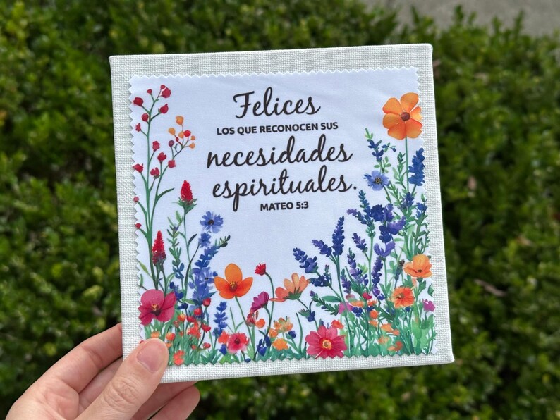 Puede incluir: Arte en lienzo cuadrado con un dise&ntilde;o floral y el texto en espa&ntilde;ol "Felices los que reconocen sus necesidades espirituales. Mateo 5:3." La obra presenta flores coloridas en tonos rojos, naranjas, azules y morados sobre un fondo blanco.
