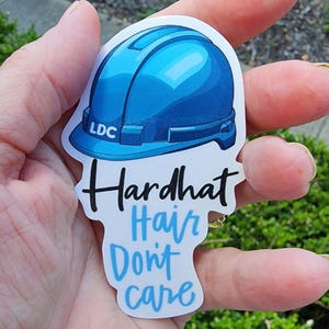 May include: A blue hard hat sticker with the text "Hardhat Hair Don't Care" and the letters "LDC" on the hard hat.