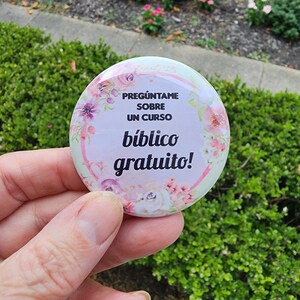 May include: A pink and white button with floral designs and the text "Preg&uacute;ntame sobre un curso b&iacute;blico gratuito!"