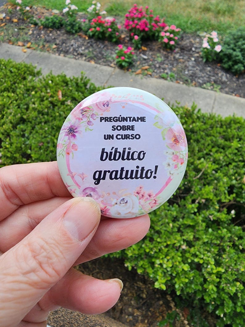 May include: A pink and white button with floral designs and the text "Preg&uacute;ntame sobre un curso b&iacute;blico gratuito!"