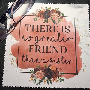 Puede incluir: Un pa&ntilde;o de limpieza de microfibra cuadrado blanco con un fondo de acuarela rosa y purpurina dorada. El pa&ntilde;o tiene un borde negro y el texto "THERE IS no greater FRIEND than a sister" en negro.
