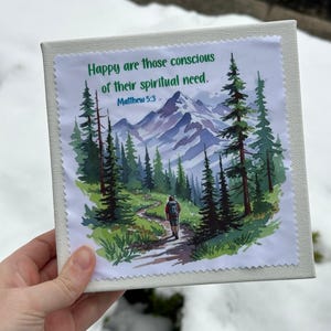 Puede incluir: Impresi&oacute;n en lienzo cuadrada con un paisaje de monta&ntilde;a en acuarela con un sendero, pinos y un excursionista. Incluye el texto "Happy are those conscious of their spiritual need. Matthew 5:3."