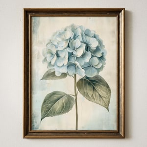 Könnte beinhalten: Gerahmter Kunstdruck mit einer blauen Hortensienblüte. Die Aquarellmalerei zeigt die Blütenblätter und grünen Blätter. Der Rahmen ist in einem dunklen, warmen Braunton gehalten.