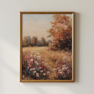 May include: A framed landscape painting featuring a field of wildflowers and tall grass in shades of yellow, pink, and white. The artwork has a gold frame and depicts a tree with orange and brown leaves. The sky is a soft, pale blue.