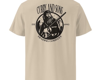 May include: A beige short-sleeve t-shirt featuring a black circular graphic on the back. The design depicts a bearded figure holding a long tool, surrounded by mountain silhouettes, with the text CURRY AND SONS TRADING COMPANY EST 1995.