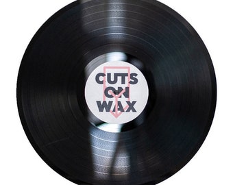 May include: A black vinyl record with a white label that says "CUTS ON WAX" in black text with a pink rectangle around the text.
