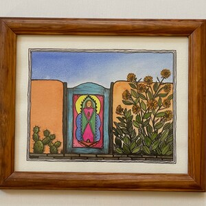 May include: A framed watercolor painting depicting a blue door with a yellow haloed figure inside. The door is set in a wall with a cactus and a bush with yellow flowers on either side.