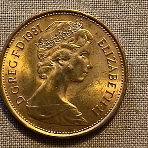 May include: A gold-colored coin with the inscription "D.G.REG.F.D. 1981" and a portrait of Queen Elizabeth II.