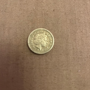 May include: A silver coin featuring the profile of Queen Elizabeth II with the inscription "ELIZABETH II D.G. REG. F.D." on one side and the year "2001" on the other side.