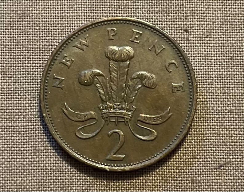 May include: A bronze-coloured two pence coin featuring the Welsh dragon with the inscription "NEW PENCE" around the edge.