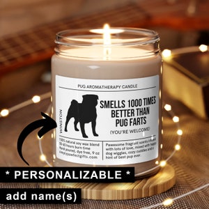 May include: A brown soy wax candle with a white label that says "Pug Aromatherapy Candle" and features a black silhouette of a pug. The label also says "Smells 1000 Times Better Than Pug Farts (You're Welcome)". The candle is 9 oz and has a burn time of 50-60 hours. The candle is personalised with the name "Winston".