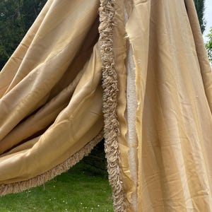 May include: A pair of beige striped curtains with a fringe trim. The curtains are made of a soft, silky fabric and have a subtle sheen.