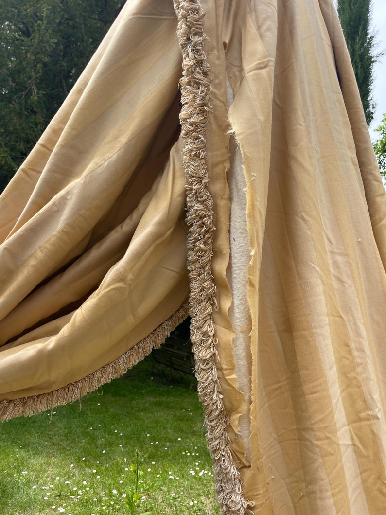 May include: A pair of beige striped curtains with a fringe trim. The curtains are made of a soft, silky fabric and have a subtle sheen.