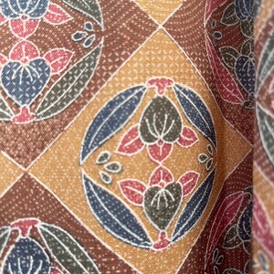 Puede incluir: Una tela con estampado marr&oacute;n, beige y azul con un dise&ntilde;o floral repetitivo. La tela tiene una superficie texturizada.