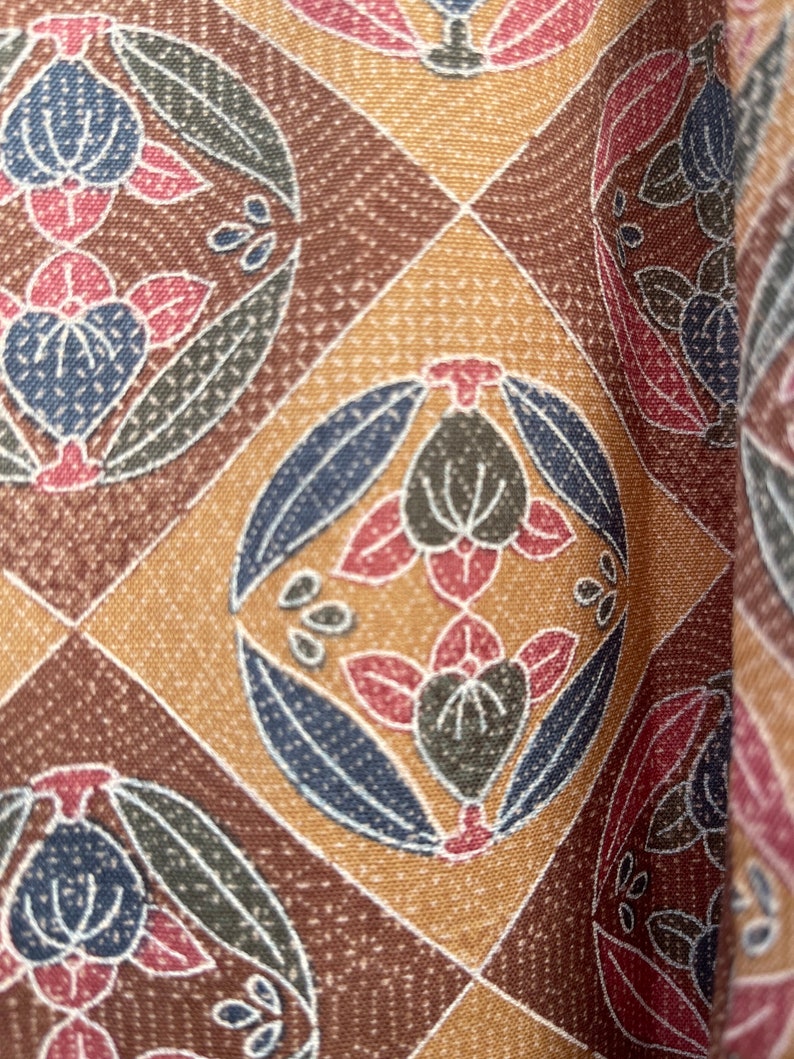 Puede incluir: Una tela con estampado marr&oacute;n, beige y azul con un dise&ntilde;o floral repetitivo. La tela tiene una superficie texturizada.