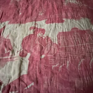 May include: A vintage fabric with a repeating pattern of a man in a hat playing a musical instrument, a building with windows, and a floral design. The fabric is a deep pink color with a white background.