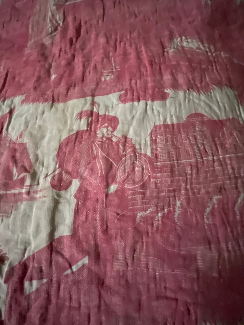 May include: A vintage fabric with a repeating pattern of a man in a hat playing a musical instrument, a building with windows, and a floral design. The fabric is a deep pink color with a white background.