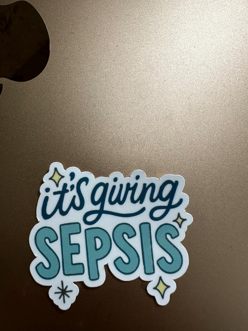 Puede incluir: Una pegatina blanca con la frase "it's giving SEPSIS" en letras turquesas y azul oscuro. La pegatina tiene un borde blanco y detalles decorativos de estrellas y copos de nieve. La pegatina est&aacute; sobre una superficie marr&oacute;n.