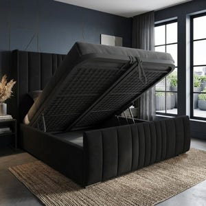 May include: A black upholstered bed frame with a tall, vertical-channeled headboard and footboard. The mattress platform is lifted at an angle by a gas-lift mechanism, revealing a hollow storage compartment underneath the bed frame structure.