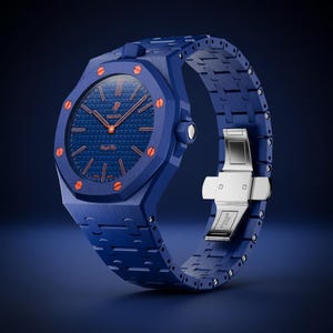 Könnte beinhalten: Eine blaue Armbanduhr mit achteckiger Lünette und orangefarbenen Schraubenakzenten, einem strukturierten blauen Zifferblatt mit orangefarbenen Zeigern und Markierungen sowie dem Text AP Swatch Royal Pro. Die Uhr hat ein blaues Gliederarmband und eine silberfarbene Metallschließe.