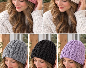 May include: A collection of five ribbed knit beanies shown in pink, cream, gray, black, and lavender. Each beanie features a thick, folded cuff and a vertical textured stitch pattern that runs from the crown down to the bottom edge of the cuff.
