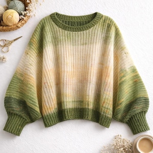 Puede incluir: Un suéter de punto verde, amarillo y crema con cuello redondo y mangas largas y voluminosas. El suéter presenta puños y dobladillo acanalados. El degradado de color transita del verde al amarillo al crema.