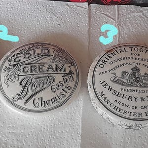 May include: Four antique ceramic containers. One reads "American Dentifrice" with text, another "Cold Cream Boots Chemists", a third "Oriental Tooth Paste", and the last has the number "16". All are white with black text.
