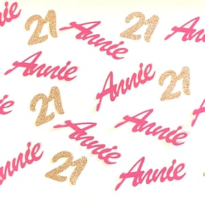 May include: Pink and gold confetti with the name "Annie" and the number "21" repeated multiple times.