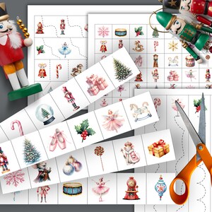 May include: Christmas-themed educational activity sheets with illustrations of nutcrackers, ornaments, and gifts. Includes cut-out strips with matching images and a pair of orange-handled scissors. A wooden nutcracker doll is also visible.