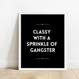 May include: A framed black and white print with the text "Classy with a Sprinkle of Gangster" in a bold, sans-serif font. The print is centered on a white background.