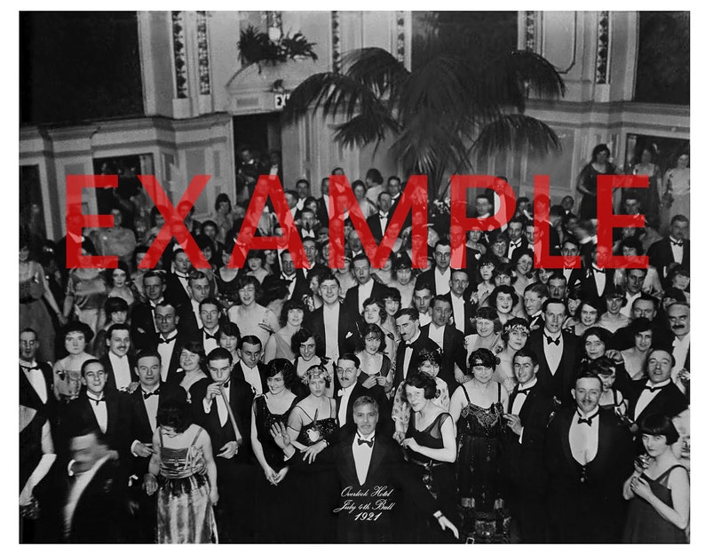 May include: Black and white photograph of a large group of people gathered in a ballroom. The people are dressed in formal attire and are smiling and laughing. The photo was taken at the  "Cranbrook Hotel July 24th Ball 1921".