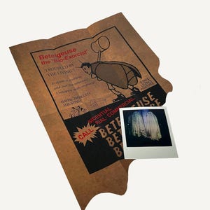 Puede incluir: Un anuncio de papel marrón doblado para un servicio llamado "Betelgeuse the 'Bio-Exorcist'". El anuncio presenta una ilustración de dibujos animados de una persona vestida de insecto sosteniendo un martillo. El texto del anuncio dice "Troubled by the Living!" y "Having difficulty adjusting". El anuncio también incluye una pequeña foto Polaroid de dos fantasmas blancos.