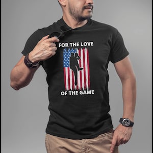 May include: Black t-shirt with a white silhouette of a baseball player against an American flag with the text "FOR THE LOVE OF THE GAME".