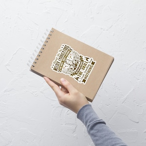 May include: A brown spiral notebook with a sticker that reads "Blessed Are The Welder Fabricators" in a stylized font. The sticker features a welder graphic and the text "The Skill To Create Something From Nothing."