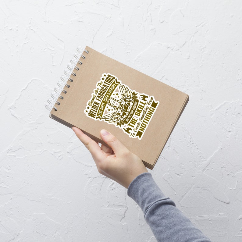 May include: A brown spiral notebook with a sticker that reads "Blessed Are The Welder Fabricators" in a stylized font. The sticker features a welder graphic and the text "The Skill To Create Something From Nothing."