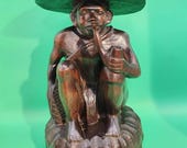 Wooden Statue of an Asian Man Sitting on His Haunches While Smoking a Pipe