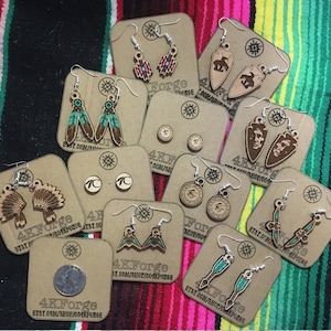 May include: Assortment of wooden earrings with various designs, including feathers, arrowheads, and Native American headdresses. The earrings are displayed on brown card stock with the text "4KForge" and a website address.