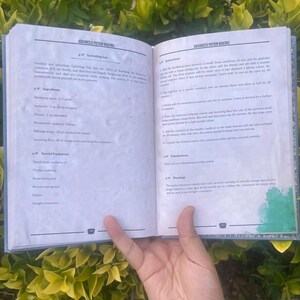 May include: An open book with the title "Advanced Potion Making" is held open, revealing detailed instructions and ingredient lists. The pages are filled with text and diagrams, with a hand holding the book open.