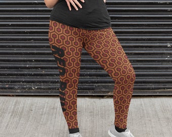 May include: A person wearing a black shirt and leggings with a red and brown geometric pattern. The leggings have the word "REDRUM" printed down the side in black.