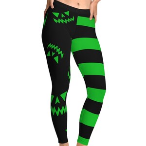May include: Black leggings with green jack-o'-lantern faces and green horizontal stripes. The leggings are form-fitting and made of a stretchy material. The design is a Halloween theme.