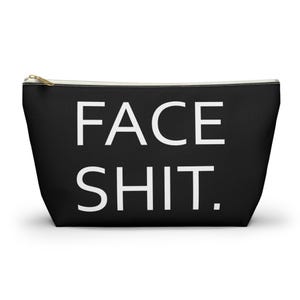 Può includere: Pochette cosmetica nera con la scritta bianca "FACE SHIT". La borsa ha una cerniera dorata e una fodera bianca. Progettata per contenere trucchi e altri prodotti di bellezza.