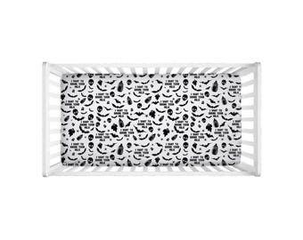May include: A white crib sheet with a repeating black pattern of skulls, bats, baby bottles, and the text "I WANT TO DRINK YOUR MILK". The sheet is designed for a baby's crib and has a Halloween theme.