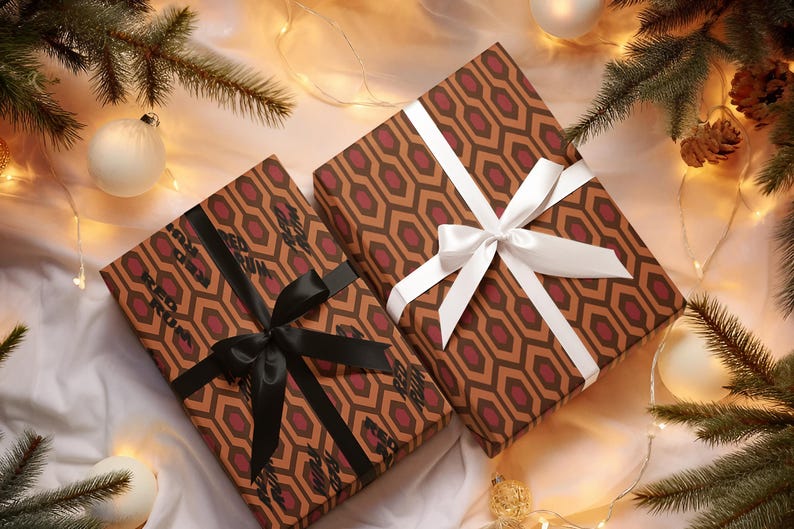 May include: Two wrapped gifts with brown and burgundy geometric patterned paper, tied with a black and white ribbon. The gifts are surrounded by Christmas decorations, including white ornaments, pine branches, and string lights.