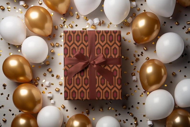 May include: A wrapped gift box with a brown geometric pattern and a matching ribbon is surrounded by gold and white balloons and gold confetti. The balloons are arranged around the gift box, creating a festive and celebratory atmosphere.
