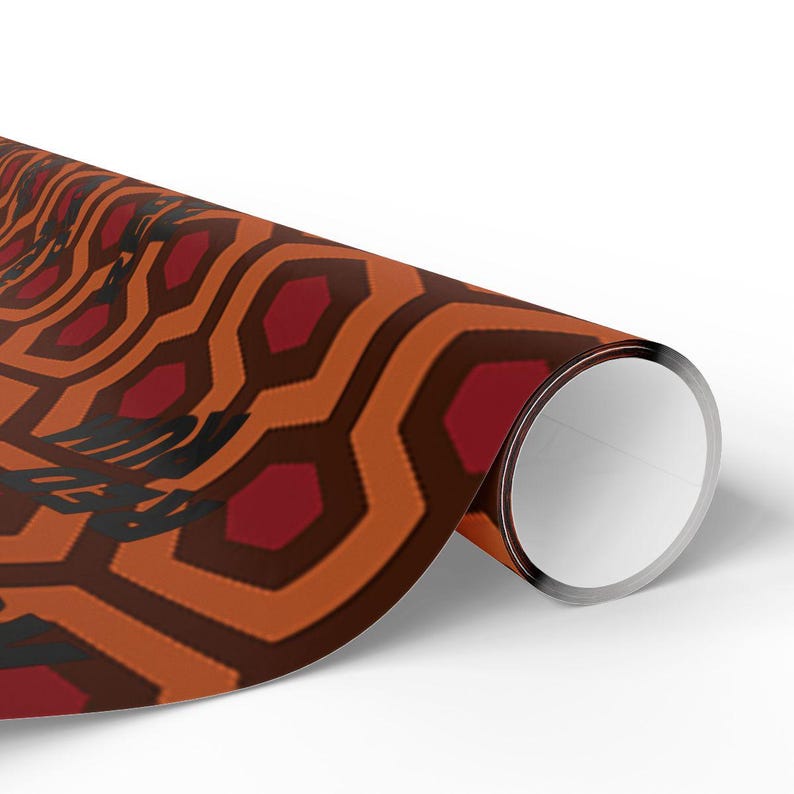 May include: Rolled paper with a repeating geometric pattern in shades of orange, brown, and burgundy. The design features a series of interconnected hexagons. The text "THE SHINING" is visible in black. The paper is rolled up.