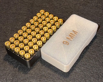 May include: A black tray filled with numerous brass-colored 9mm bullets, next to a light gray case with the text "9 MM" embossed on the top. The bullets are arranged neatly in rows.